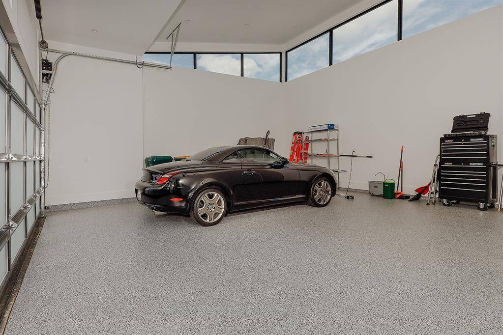 This is a spacious, well-lit garage with a high ceiling and a large window allowing for natural light. Epoxy-coated floor and is equipped with storage and workspace areas, suitable for vehicle parking and hobbies.  Air Conditioned storage area houses whole house water filtration, water softener and two 50 gallon natural gas hot water heaters w/a recirculating loop system.  Two EV outlets.