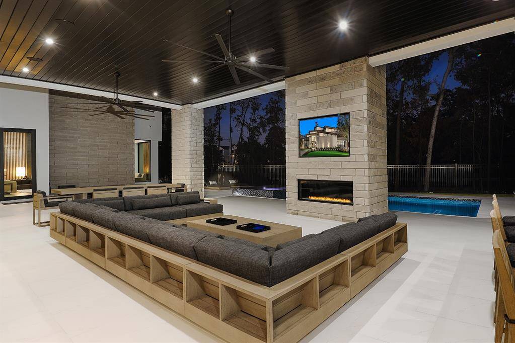 Featuring a sleek stone gas fireplace with a mounted all weather Samsung TV and an inviting pool view. The area is ideal for large gatherings or relaxing.