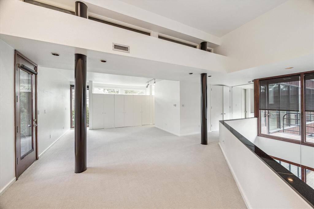 Primary bedroom. Door to the left is to the balcony. Far wall begins a lengthy wall of closets through to both bathrooms.