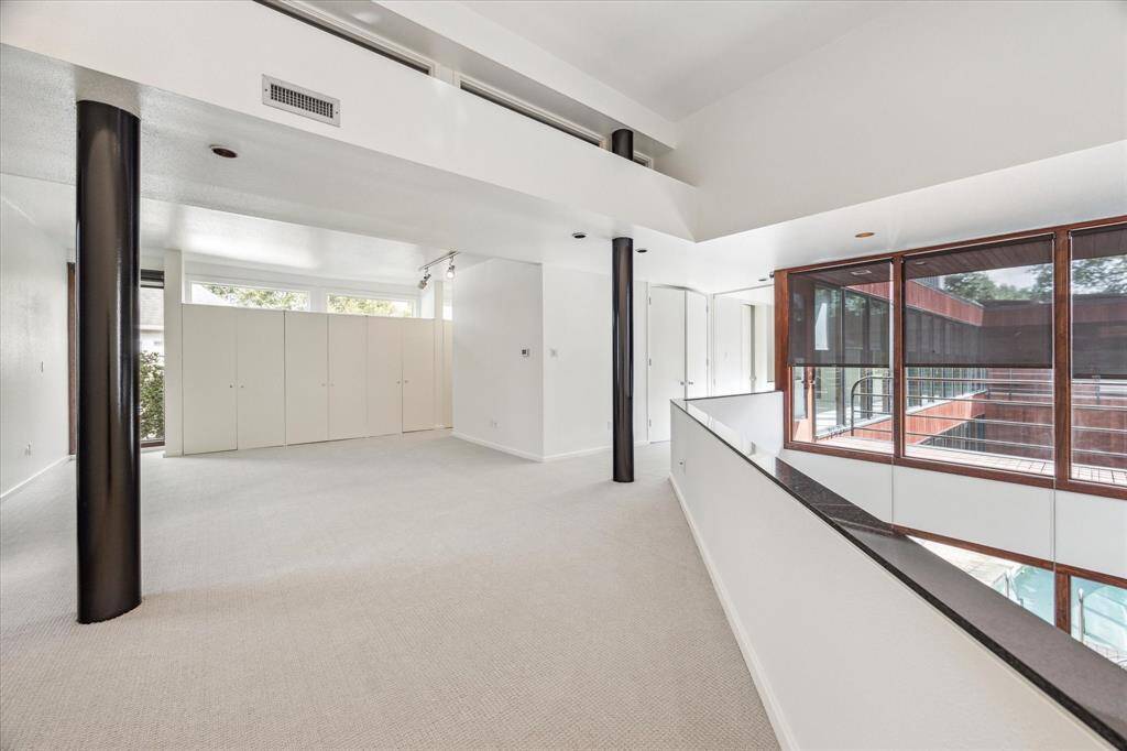 A view of the second story of the upstairs and outside of the home.  A balcony is off the primary bedroom hall.