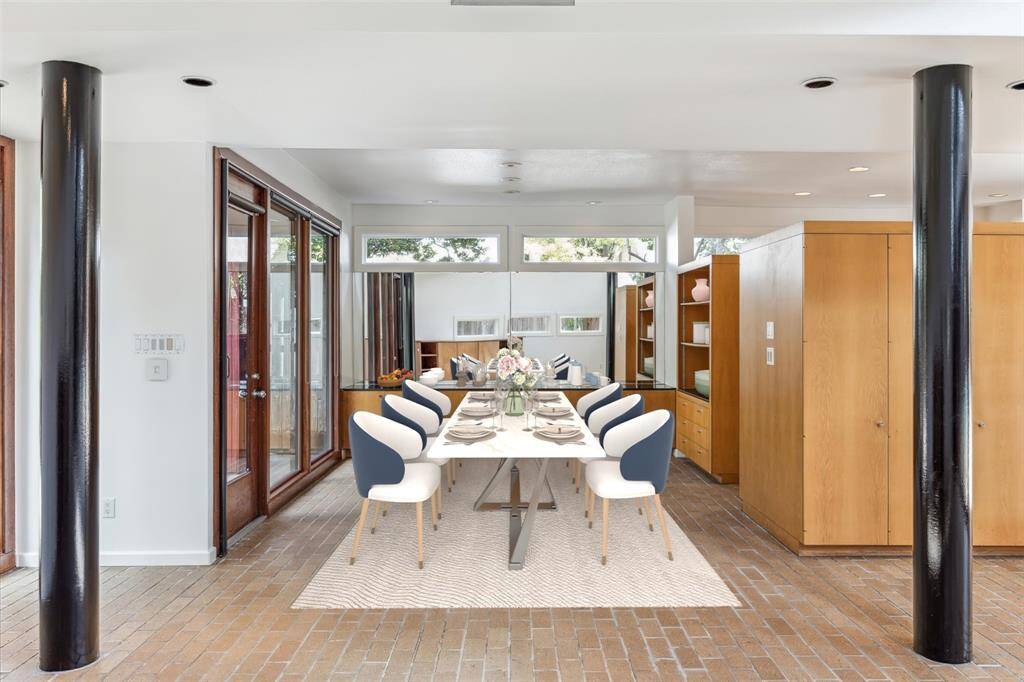 A view of the dining room a mirrored wall and built-in cabinets. The kitchen it to the right. Virtually staged.