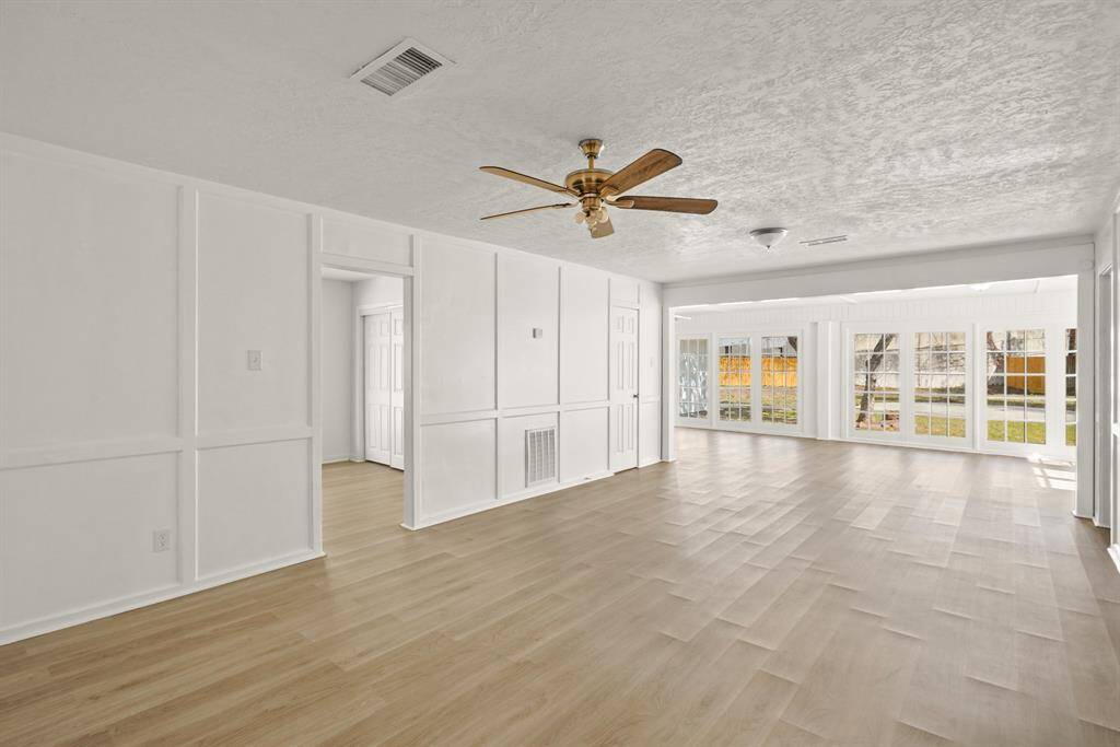 As we step into the expansive sunroom, you can enjoy the newly installed flooring under the natural light streaming in through the numerous windows.