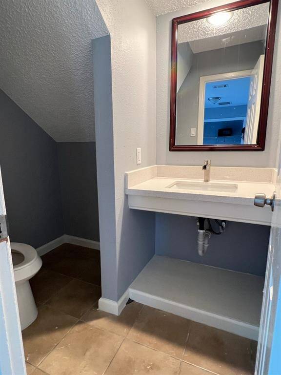 This is a compact half-bath featuring a wall-mounted sink, mirrored medicine cabinet, and toilet, with tile flooring and two-tone wall paint.