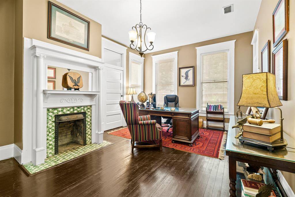 This Office shares the other side of the dual-sided fireplace. This space is equipped with original hardwood flooring, cased windows, cased doors, and a 3-light chandelier.