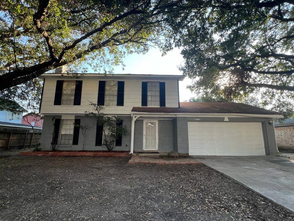 This is a two-story home with a mix of siding and brick facade, featuring a two-car garage and a mature tree in the front yard, casting shade over a portion of the property.