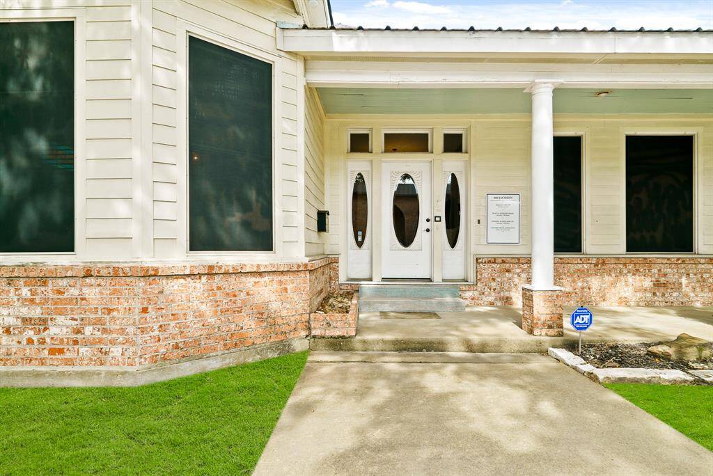 Guests will enter through this impressive, glass-plated door with coordinating sidelights and trio of transoms above. The built-in brick garden bed to the left of the door is the perfect place to plant colorful flowers that create a warm welcome.
