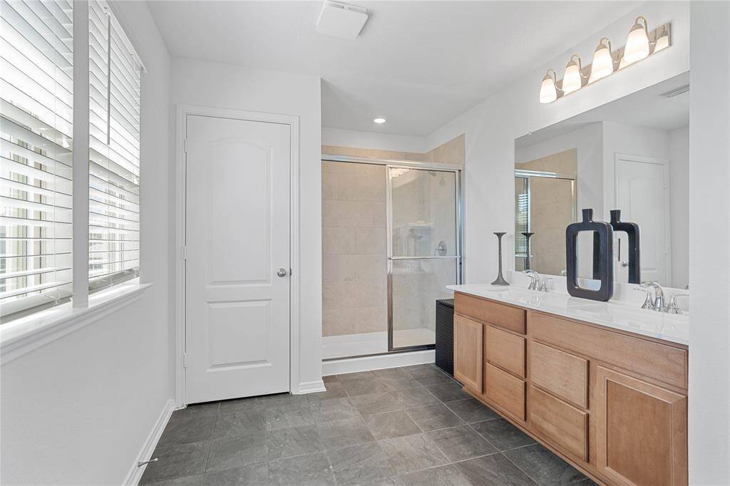 This primary bathroom is definitely move-in ready! Featuring an walk-in shower with tile surround, stained cabinets with light countertops, dual vanities, high ceilings, large windows, neutral paint, sleek and modern finishes.