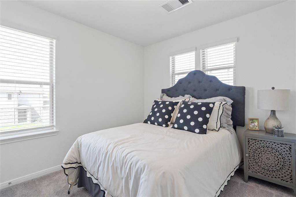 Secondary bedroom features plush carpet, neutral paint, lighting, large windows, and ample sized closet space.