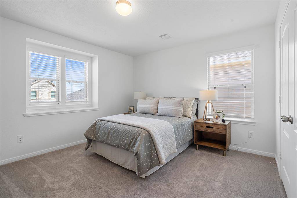 Secondary bedroom features plush carpet, neutral paint, lighting, large windows, and ample sized closet space.