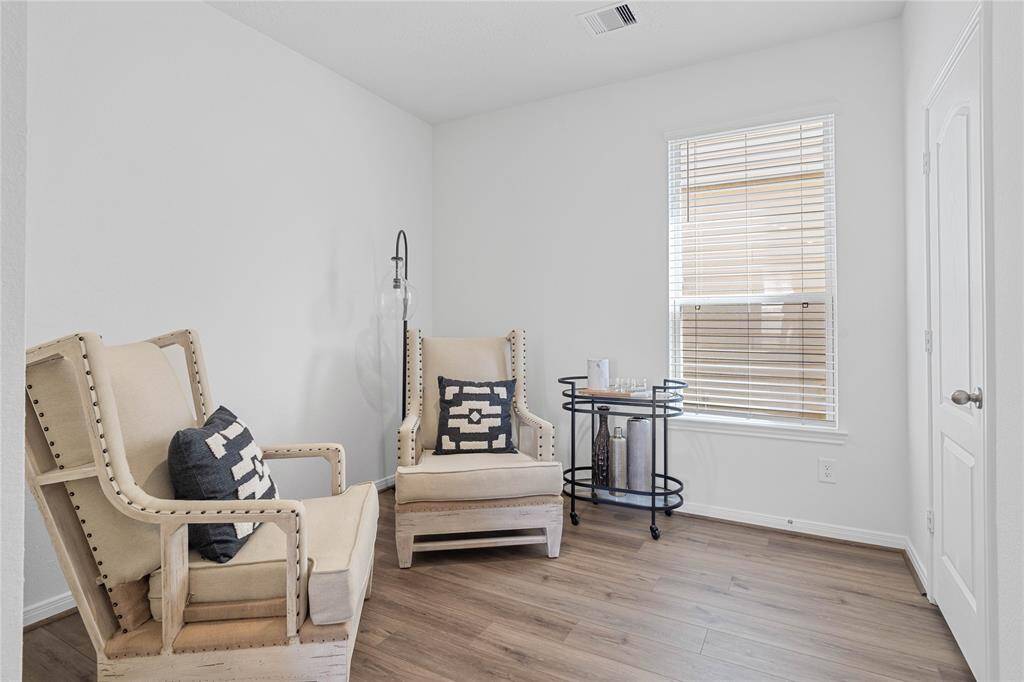 Quietly nestled in the home is the handsome den that can be used as an office, sitting room, play room, or formal dining/living room. Featuring gorgeous vinyl plank flooring, high ceilings, large window with privacy blinds and neutral paint.