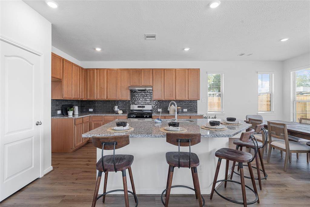 WOW! This kitchen will not disappoint! Your family and guests will enjoy many nights of fun, food and entertainment with ample counter space and kitchen island for setting up a wonderful array of provisions! This gorgeous kitchen showcases SS appliances, granite countertops, beautiful tile backsplash, gas range, high ceiling, recessed lighting and vinyl plank floors!