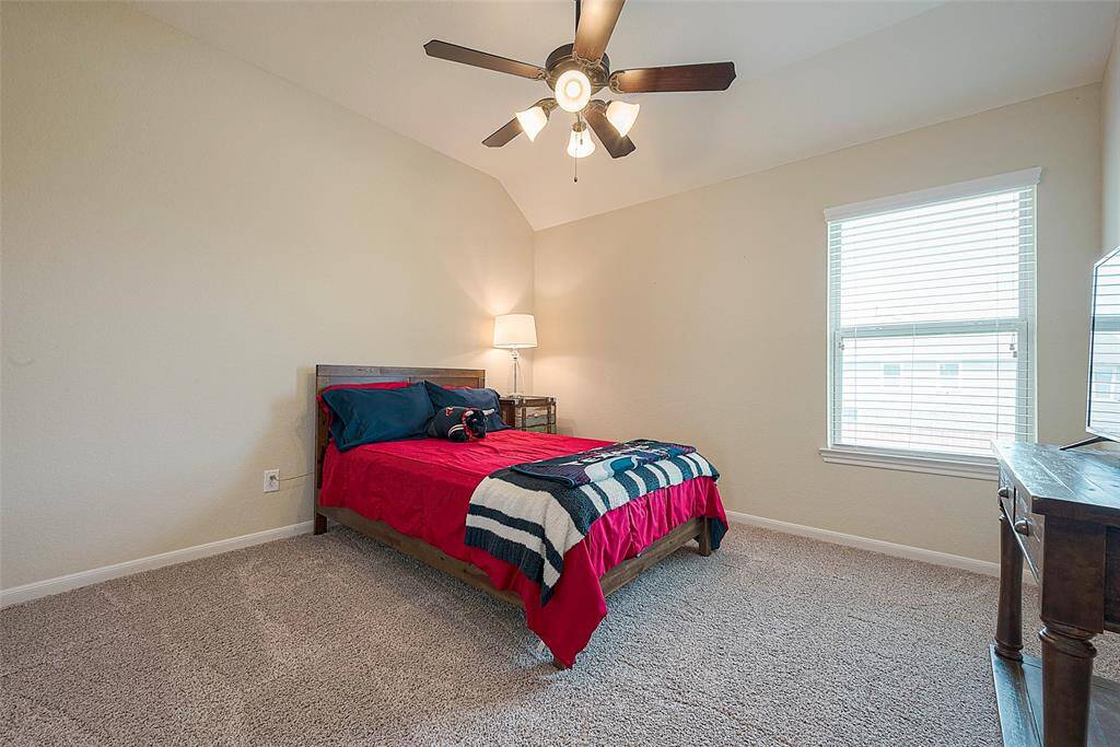 Cozy and inviting bedroom with abundant natural light, plush carpeting, and a modern ceiling fan. Perfect for relaxation and comfort.