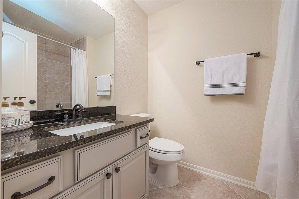 Elegant full bathroom featuring a sleek vanity, modern fixtures, and a spacious shower area. Perfect for guests or family use.