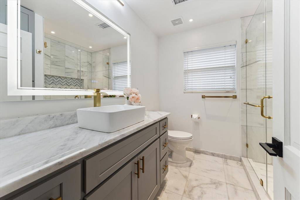 Secondary bathroom with walk in shower with marble tiles, linear shower drain, LED bathroom mirror with anti fog, dimming and waterproof features, vanity cabinet with vessel sink, custom marble/quartzite countertops and luxury hotel style dimmable recess lights