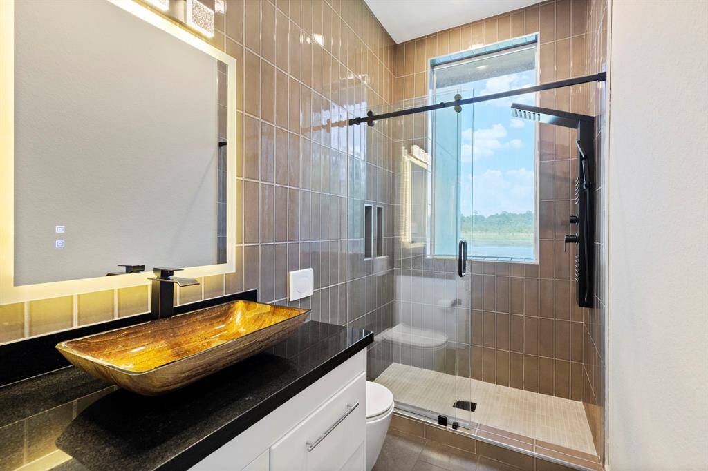 Natural light illuminates this beautiful bath with sliding glass door tub shower combination and a generous vanity.