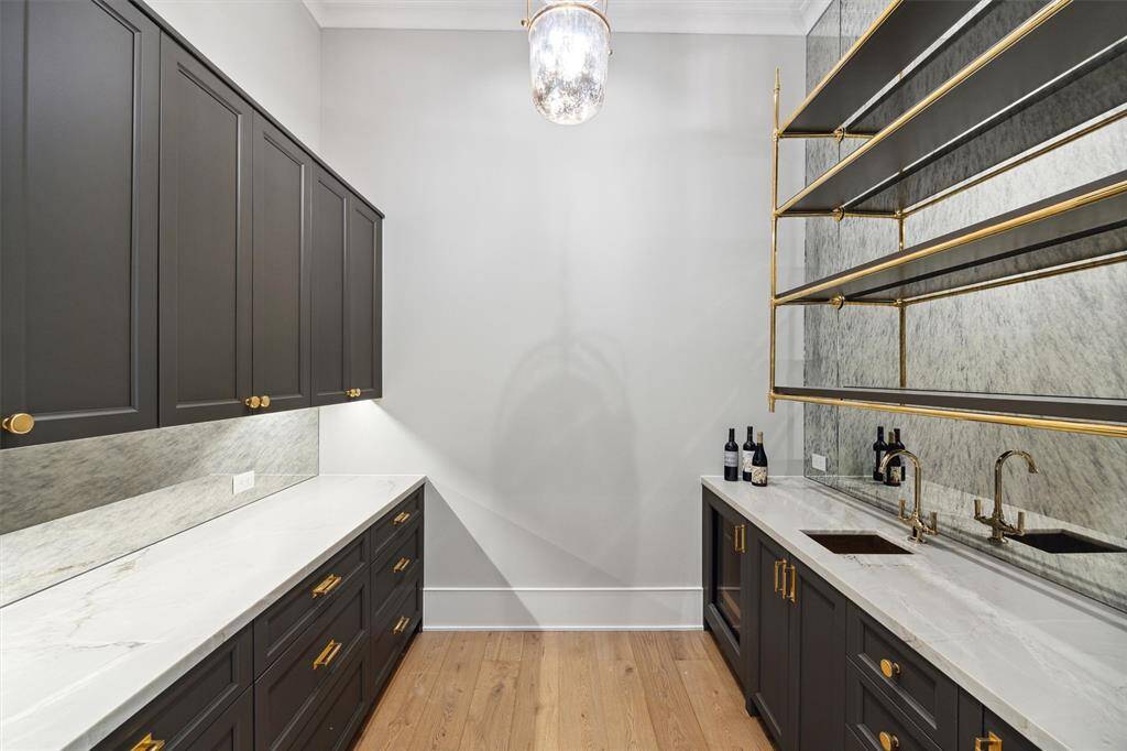 Wet bar with ice maker, beverage fridge, custom cabinetry, custom brass shelving, and antiqued mirrors.