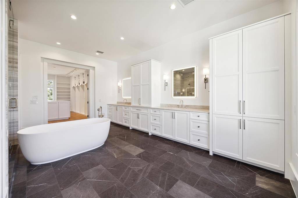 Oversized Primary bath with custom cabinetry, lighted mirrors with fog control and stand alone tub