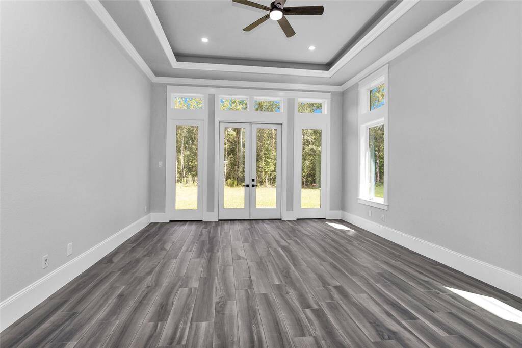 The Primary Suite offers a luxurious haven with frameless double doors opening to the backyard surrounded by a wall of windows & transoms with beautiful millwork and tray ceilings.