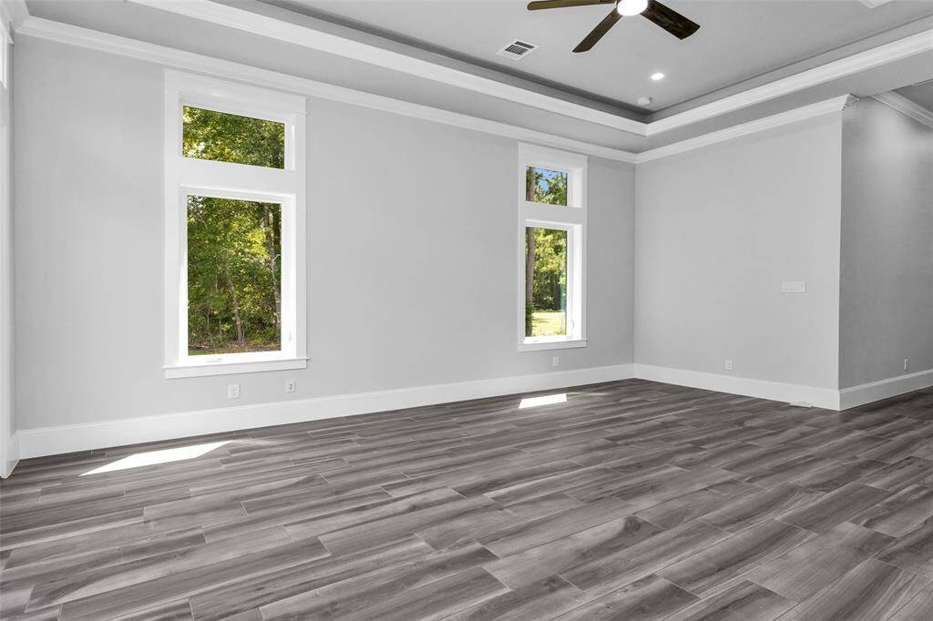 The Primary Suite glows under abundant natural light from multiple windows, and an elegant coffered ceiling that adding architectural interest.