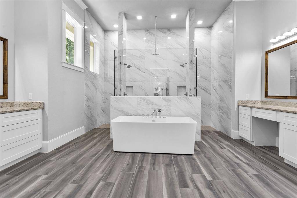 The spacious Primary En Suite Bathroom features a spa-inspired standalone bath nestled in front of a dramatic oversized shower with frameless glass.