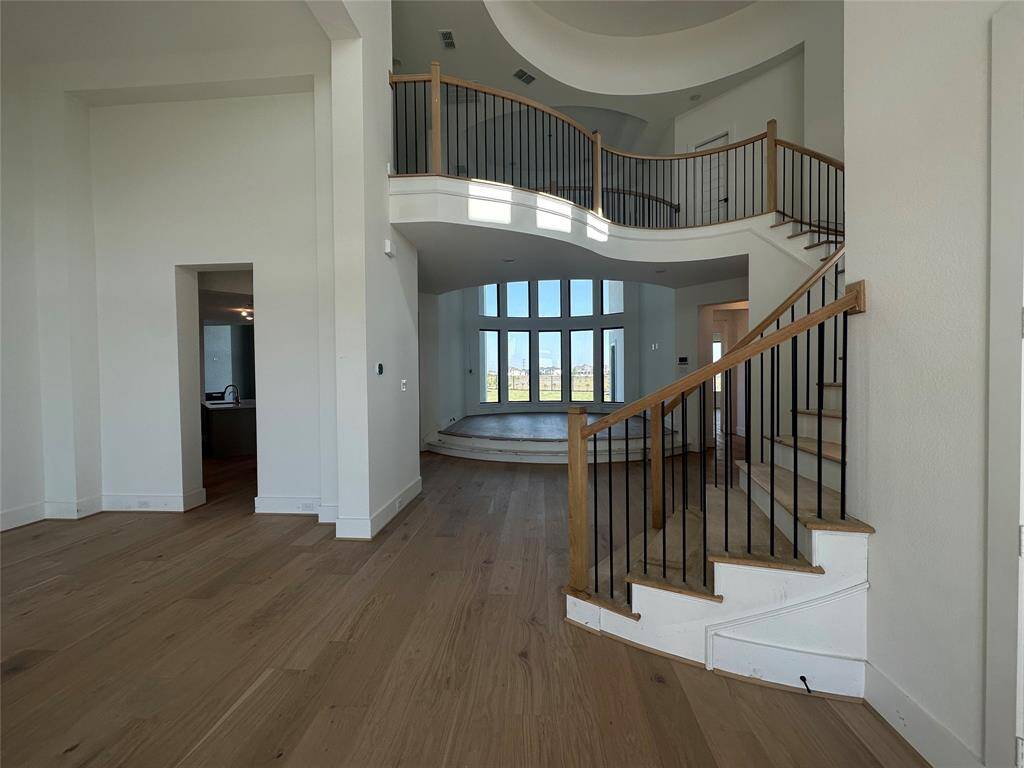 Grand Foyer view entering through the gorgeous double iron front doors with sites into the elegant Formal Dining Room, elevated two-story Living area, winding staircase and curved catwalk with lots of design appeal is coming along beautifully. Gorgeous hardwood flooring is soon to come that will run throughout.