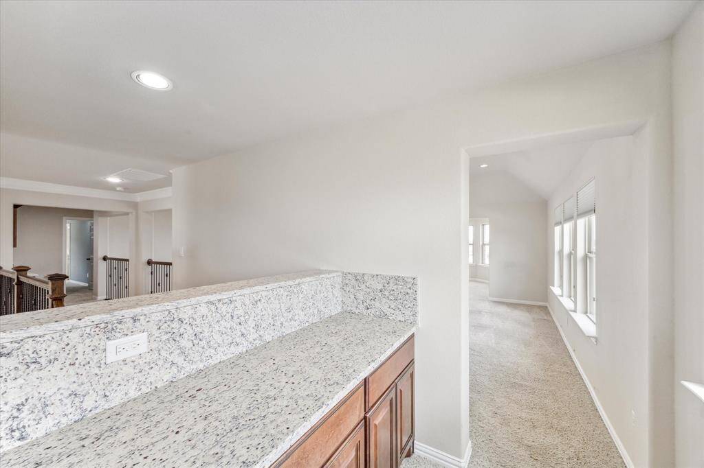 As we leave the home theater, we are passing the serving bar/entertainment area and heading into the game room. You can see the stair railings over the top of the backsplash. Secondary bedrooms and a homework station are just beyond.