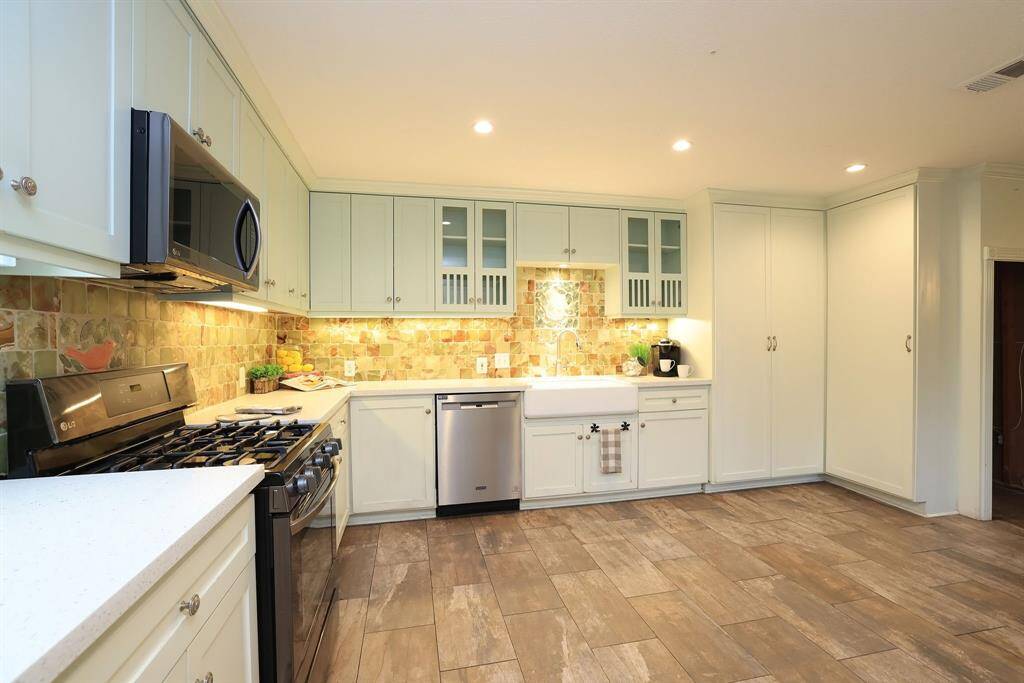 The two-tone color of the upper and lower cabinets provides visual interest and helps break up the space, and the under cabinet lighting not only provides task lighting but makes the custom marble back splash sparkle.