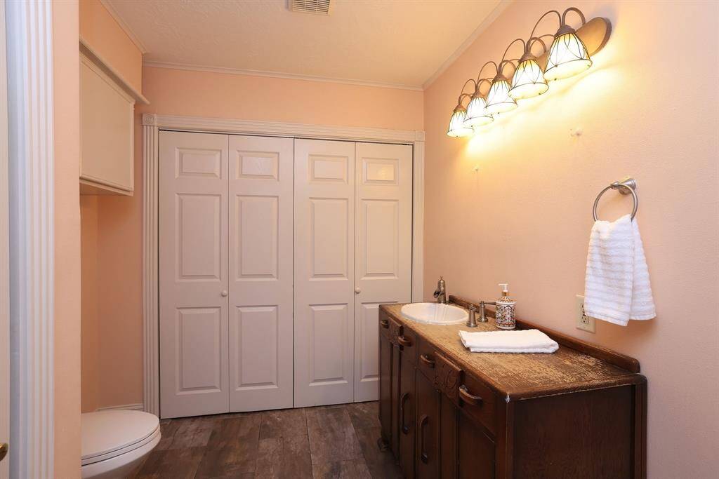 The downstairs Guest Bath includes an antique buffet turned vanity, large storage closet, and the home's laundry room- neatly hidden behind the bi-fold doors.