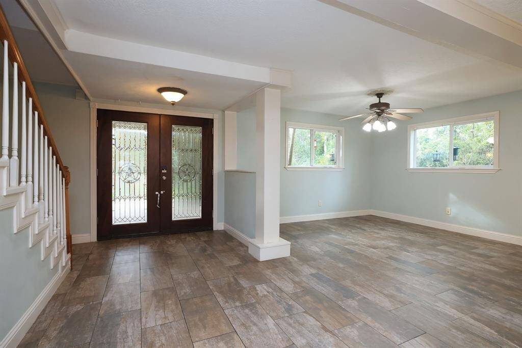 The Welcoming front entry includes dark stained double doors with wrought iron accents and rain glass, wood look tile flooring, and tons of natural light. Soft grey/blue paint offers a neutral palette that will provide the perfect backdrop for any decorating style.