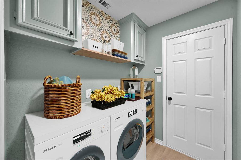 Designer tiles and paint have transformed this into a modern laundry room! There is a built-in ironing board on the opposite wall for your ease and convenience!