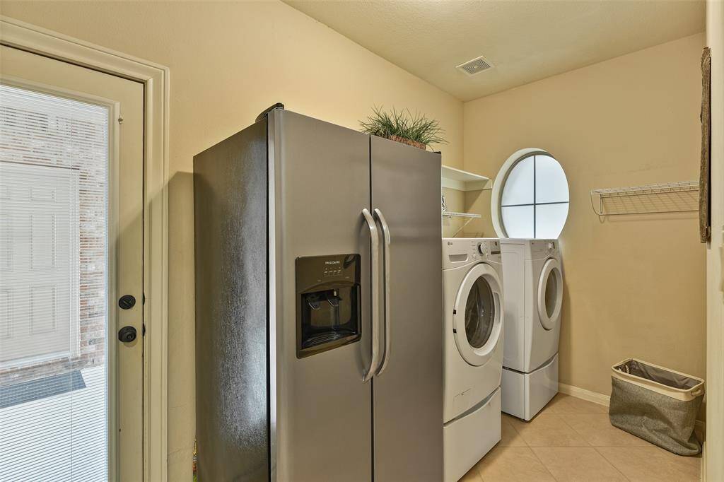 Located just inside the door from the port cohere and near the kitchen, this roomy utility room makes a great space for kicking off muddy shoes! Note the durable tile flooring, neutral paint, porthole window, and space for a bonus refrigerator.