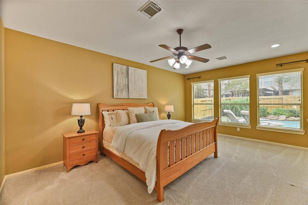 The owner's retreat is secluded at the rear of the first floor, just off of the family room. This space features a lighted ceiling fan, neutral paint, plush carpeting, and wall-to-wall windows with 2-inch blinds and tranquil pool views.