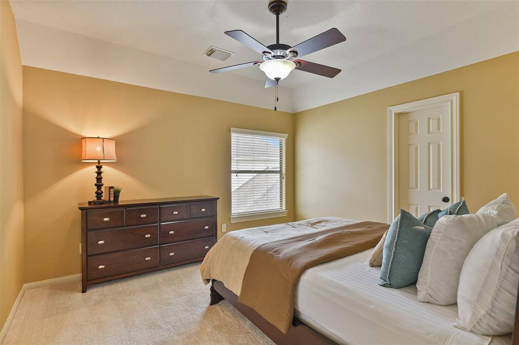 All three secondary bedrooms are located on the second floor and this one offers neutral paint, a gambrel ceiling with a lighted ceiling fan, plush carpet, a walk-in closet, a window shaded by 2-inch blinds, and a shared Jack & Jill style bathroom.