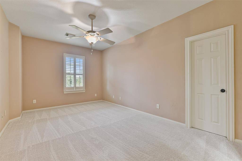 In another secondary bedroom, note the neutral paint, lighted ceiling fan, window shaded by plantation shutters, plush carpet, a roomy walk-in closet with walk-in attic access, and a shared Jack & Jill style bathroom.