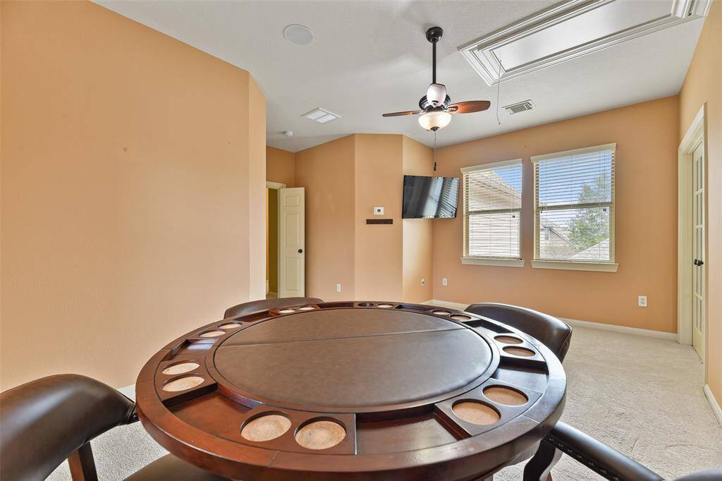 Just off of the game room, there's another space that's perfect for a poker room! Note the lighted ceiling fan, ceiling speakers, neutral paint, French doors, attic access, plush carpet, and a pair of rear-facing windows shaded by 2-inch blinds.