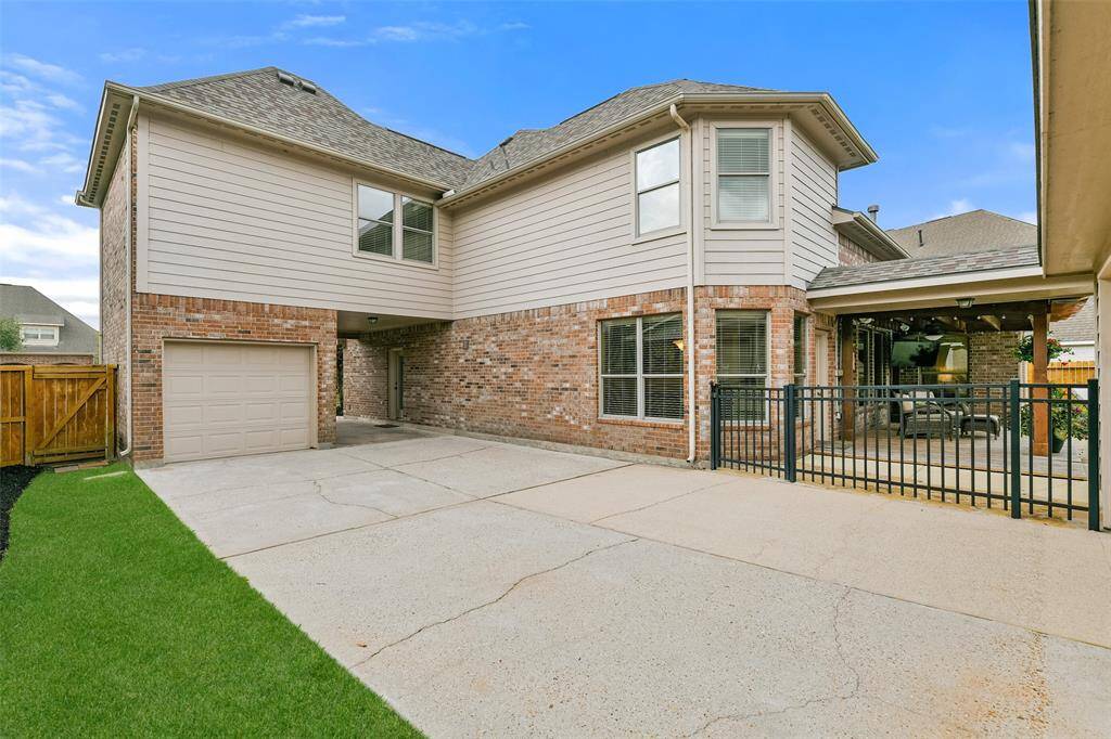 This home boasts ample parking space with a port cochere to a single garage plus a separate two-car garage and plenty of concrete parking or playing space in between, with an iron fence to the backyard area.