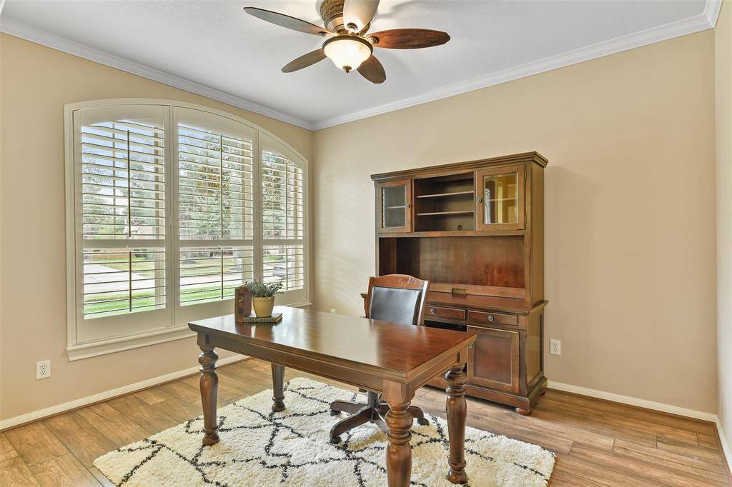 Upon entering, to the left of the foyer, a wide entrance leads into this handsome study with a lighted ceiling fan, neutral paint trimmed with crisp white crown molding, wood-look laminate floors, and a palladium arched window dressed with plantation shutters.