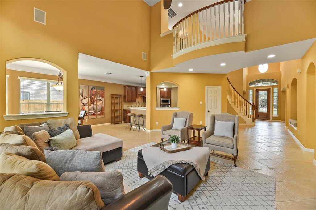 The foyer spills into this grandiose family room with a soaring two-story ceiling trimmed with crown molding, a quaint Juliet-style balcony, surround sound speakers, diagonally laid ceramic tile floors, and a convenient pass-through serving bar to the kitchen.