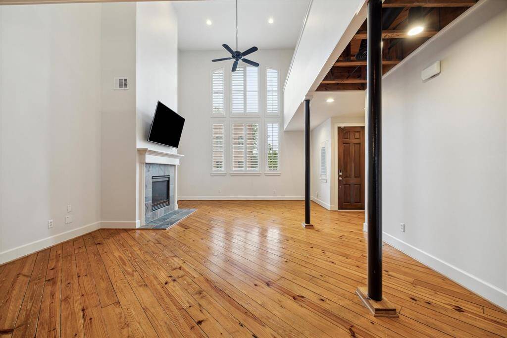The living area has a 2-story tall ceiling and windows along with a beautiful gas fireplace and wall mounted TV.