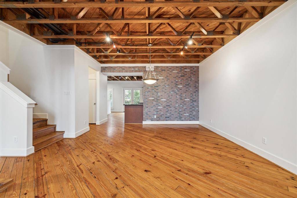 A veneer brick wall and exposed beams are placed along the open concept dinning area attached to the living space.