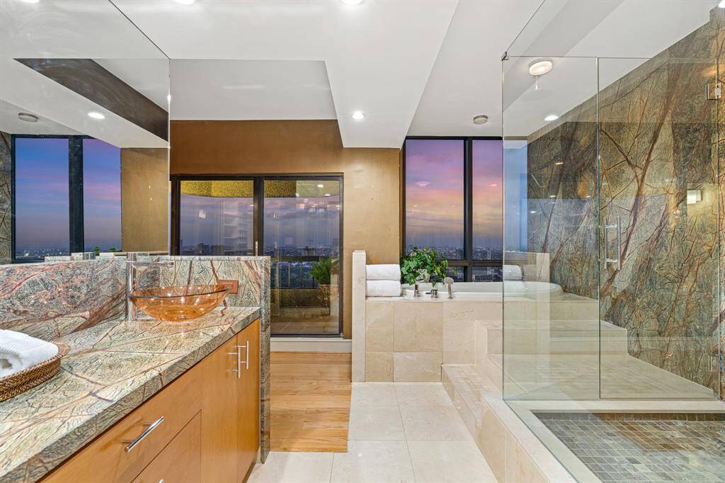 Primary bathroom with double sink vanity, oversized seamless glass shower and balcony access.