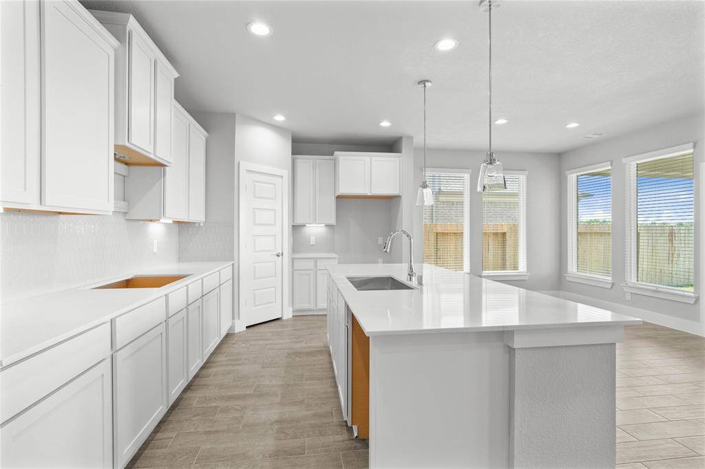 This kitchen is by far any chef’s dream! This spacious kitchen features high ceilings, stained wood cabinets, quartz countertops, SS appliances, modern tile backsplash, recessed lighting, pendant lighting, kitchen island with space for breakfast bar, and a walk-in pantry all overlooking your huge family room.