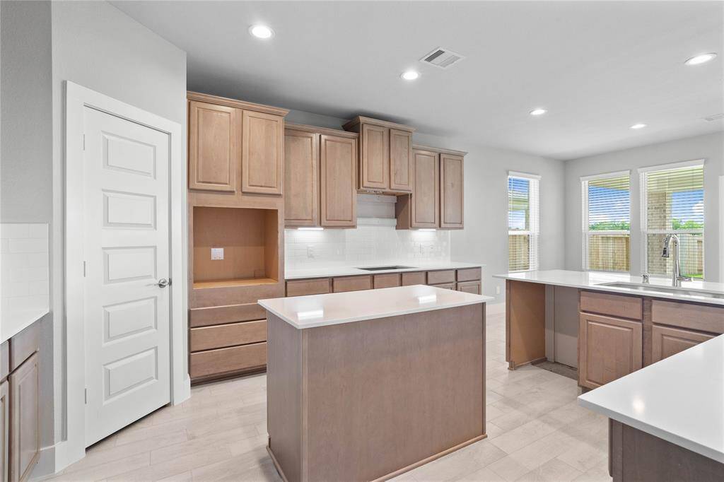 This private vanity features stained wood cabinets, beautiful light countertops, mirror, dark, sleek fixtures and modern finishes. Additionally, the shared secondary bath features tile flooring, bath/shower combo with tile surround.