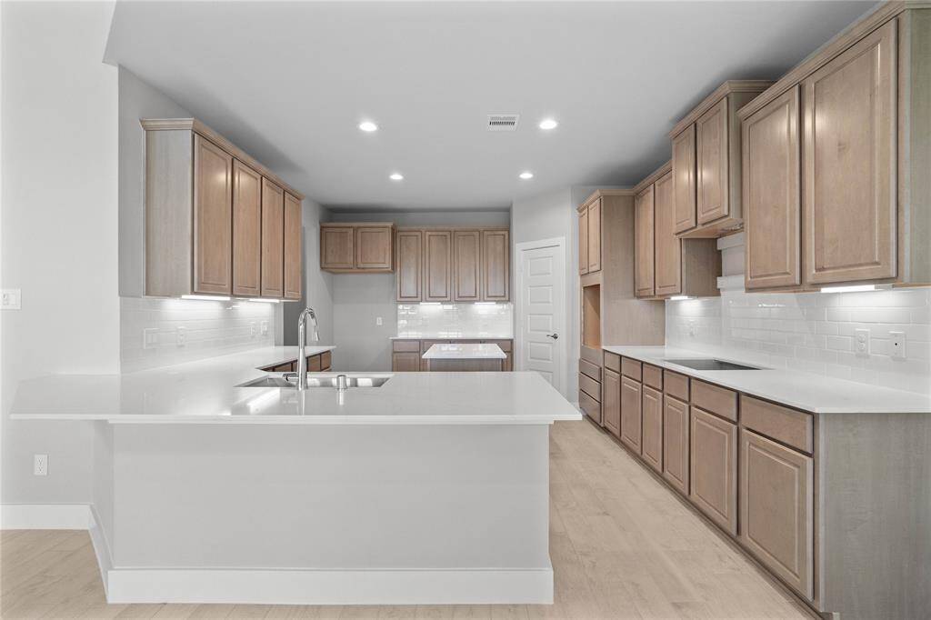 This private vanity features stained wood cabinets, beautiful light countertops, mirror, dark, sleek fixtures and modern finishes. Additionally, the shared secondary bath features tile flooring, bath/shower combo with tile surround.