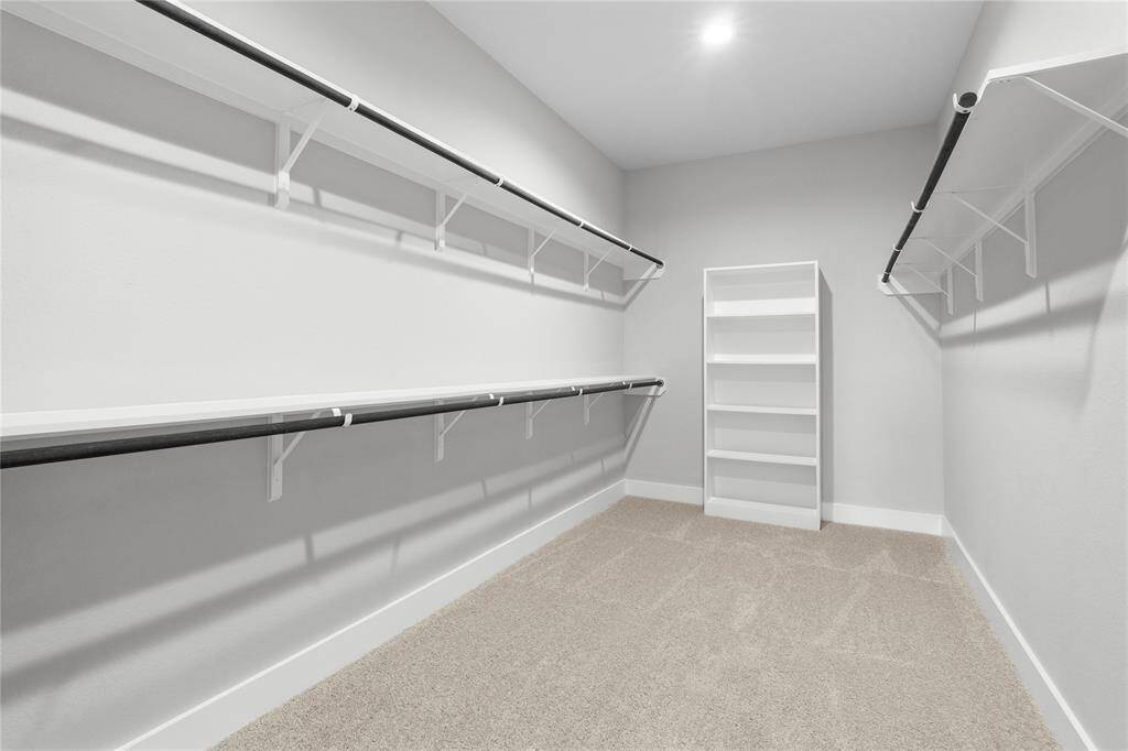 Secondary bedroom features plush carpet, custom paint, ceiling fan with lighting and a large window with privacy blinds.