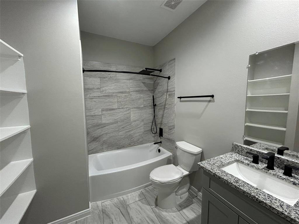 This modern bathroom features elegant tile, a deep soaking tub that includes a 10-inch rain shower, and sleek black accent fixtures. The spacious vanity and built-in shelving provide both style and storage for all your essentials!