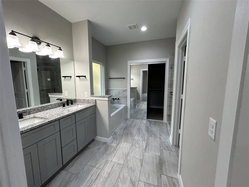 This stunning bathroom off the primary bedroom features a separate jacuzzi tub, perfect for relaxing, a walk-in shower with a rain head, making for a refreshing experience, and the double vanity offering plenty of counter space and storage. Hidden behind full length mirror doors, is the large walk-in closet!