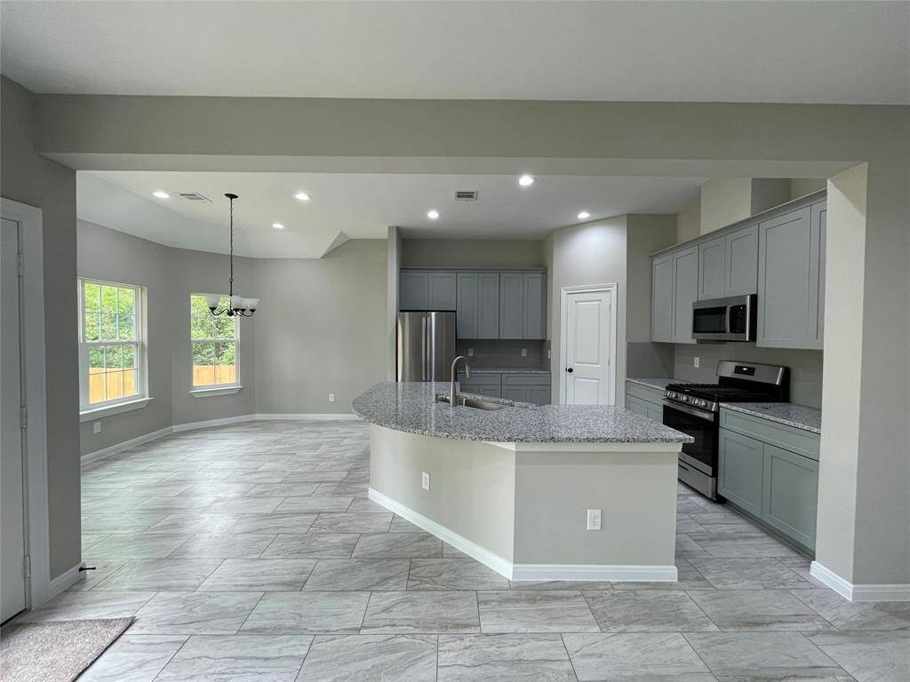 This dream kitchen includes chic gray cabinets, sparkling granite countertops, and stainless steel appliances. The curved island is perfect for gathering, and the sunny dining nook offers beautiful backyard views!