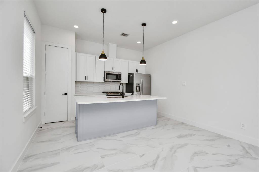 Delight in meal prep or host elegant dinner parties in this tastefully appointed open concept kitchen dining area, enhanced by the soft glow of recessed lighting and elegant light fixtures