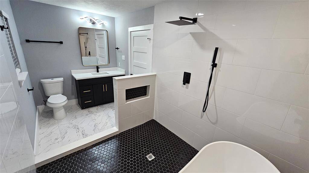 Elegant Primary Bathroom with Matte Black Vanity with Brushed Gold Accents and Modern LED Lighting